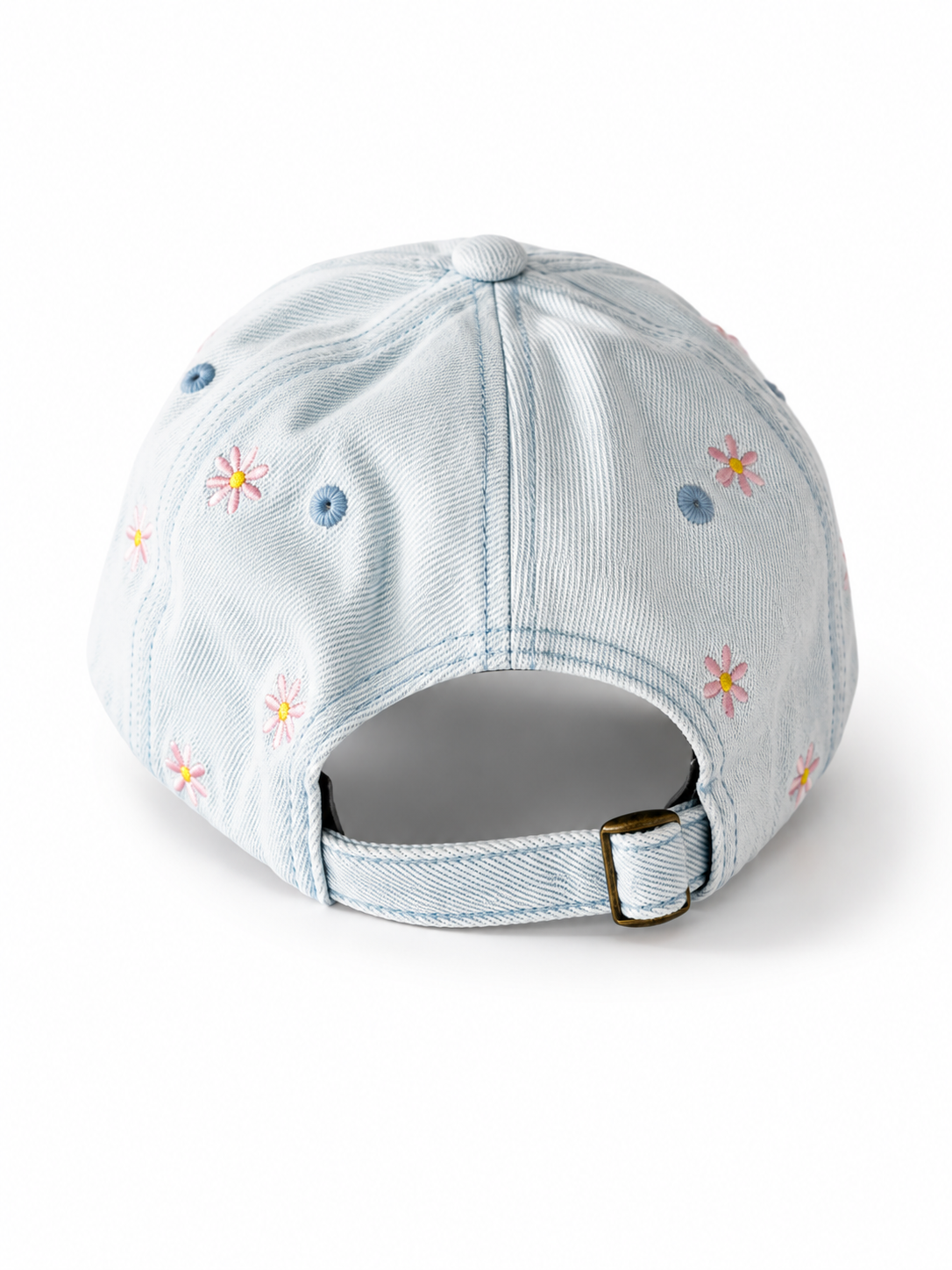 Back view of the light-wash flower-embroidered cap, showing the curved crown and the adjustable strap clipped into its brass buckle.