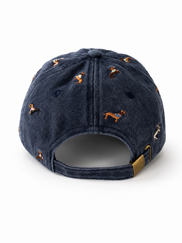 Back view of the navy dachshund-embroidered cap, showing the curved crown and the adjustable strap clipped into its brass buckle.