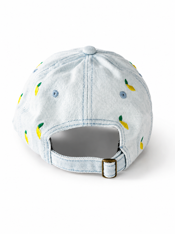 Back view of the light-wash lemon-embroidered cap, showing the curved crown and the adjustable strap clipped into its brass buckle.