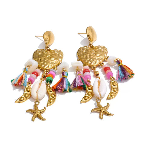 Gold heart drop earrings with rainbow cotton tassels, pink and white beads, a cowrie shell, gold pea pod charms and a gold starfish