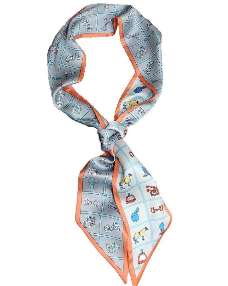 A light blue silk scarf with a grid pattern of small colorful illustrations and a bright orange border, styled in a loop and knot on a plain white background.