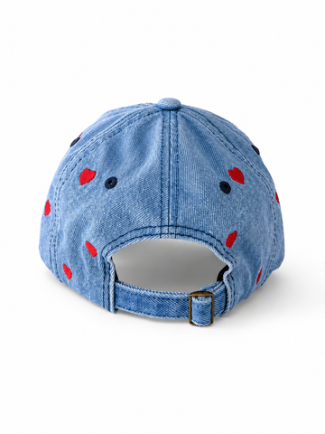 Back view of the mid-wash heart-embroidered cap, showing the curved crown and the adjustable strap clipped into its brass buckle.