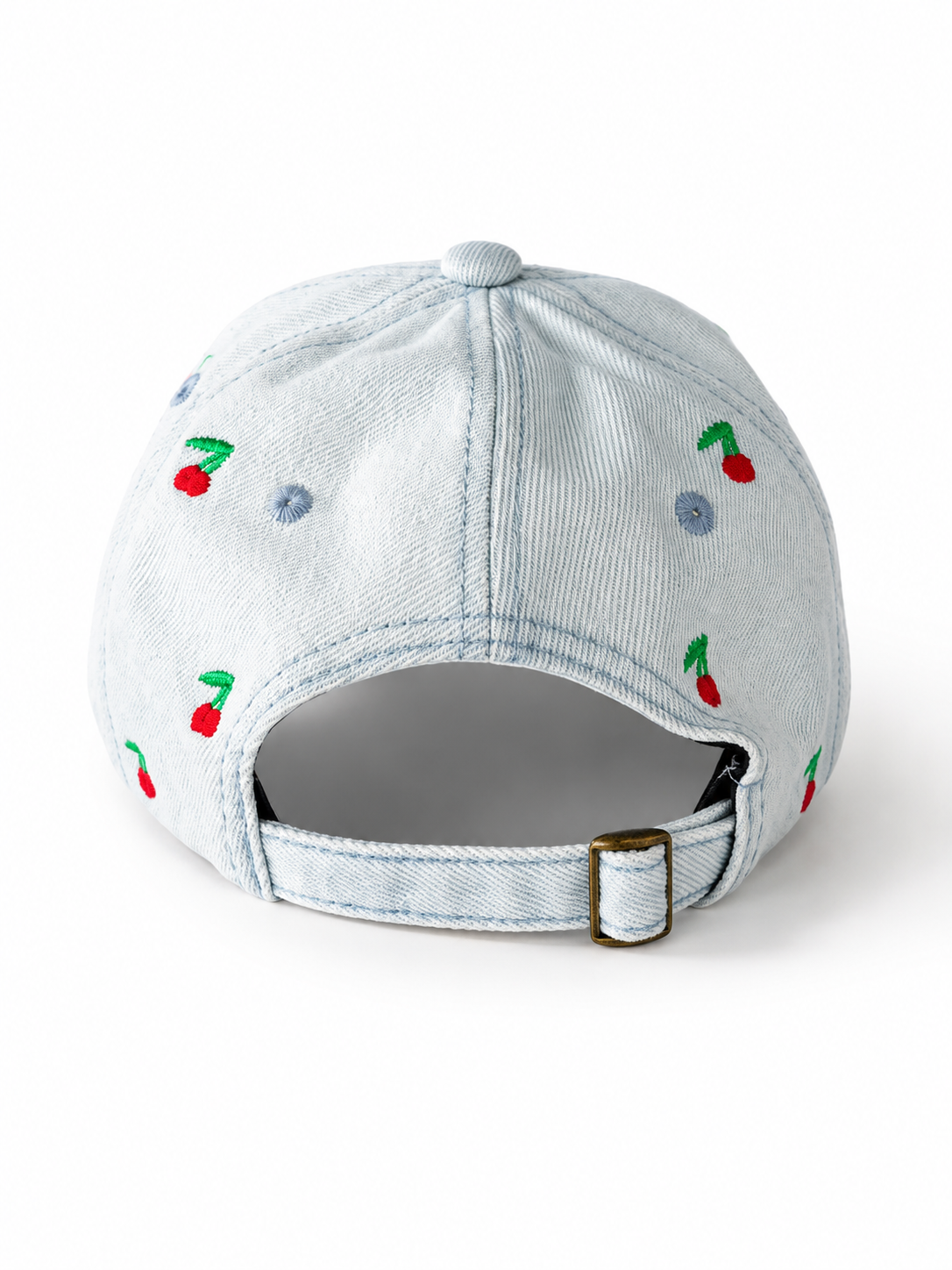 Back view of the light-wash cherry-embroidered cap, showing the curved crown and the adjustable strap clipped into its brass buckle.
