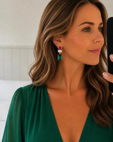 A woman wearing a green gemstone drop earring with a white pearl and pink top stone, shown in a close-up profile shot.