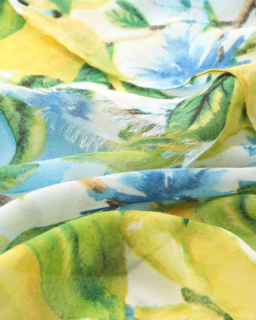 Close-up of yellow and blue watercolour lemon and blossom print scarf with frayed edge