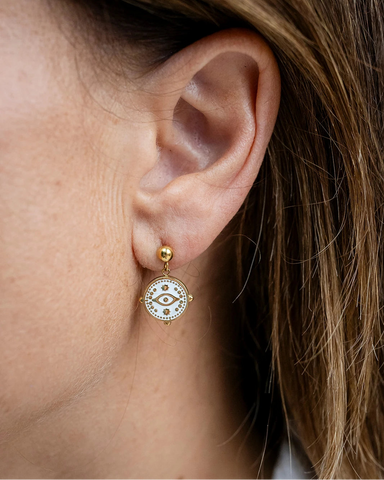 Gold stud earrings with a white enamel evil eye charm dangle