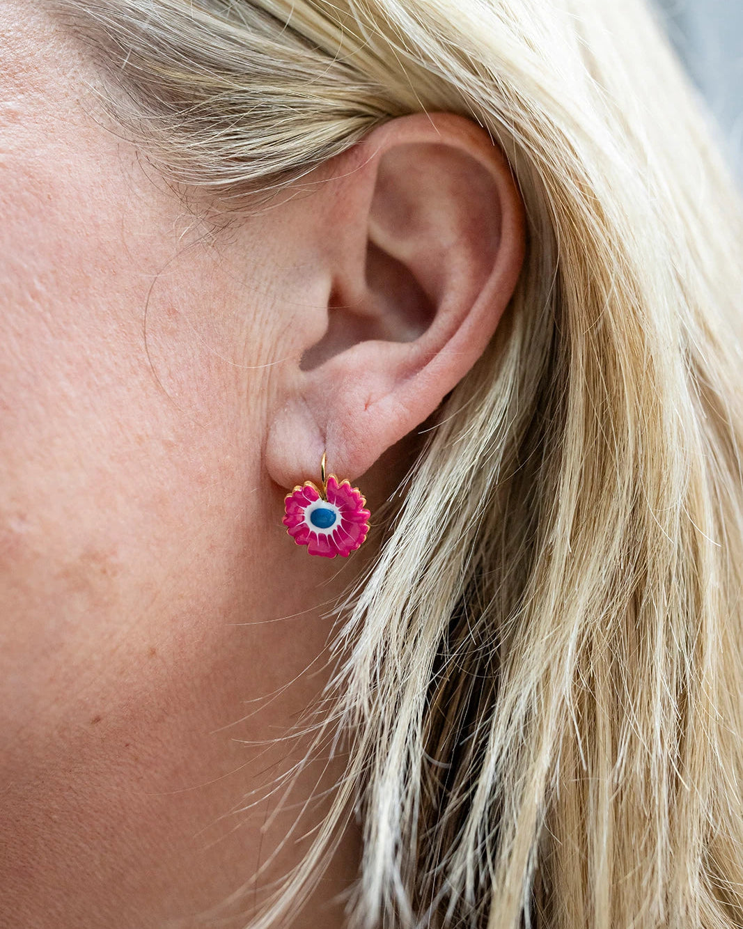 Gold hoop earrings with a pink enamel zinnia flower charm and blue centre