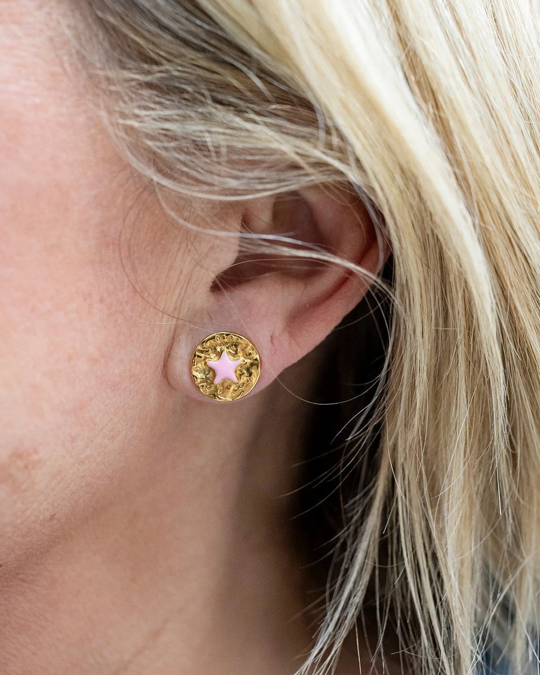 Gold stud earrings with a pink enamel star at the centre