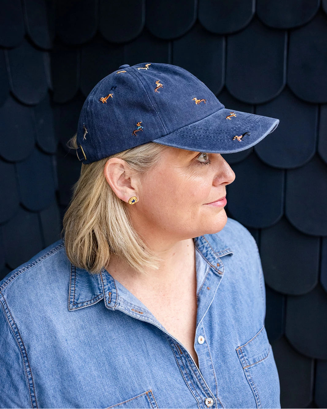Navy denim baseball cap embroidered with colourful dachshund dogs, front view on a white background.