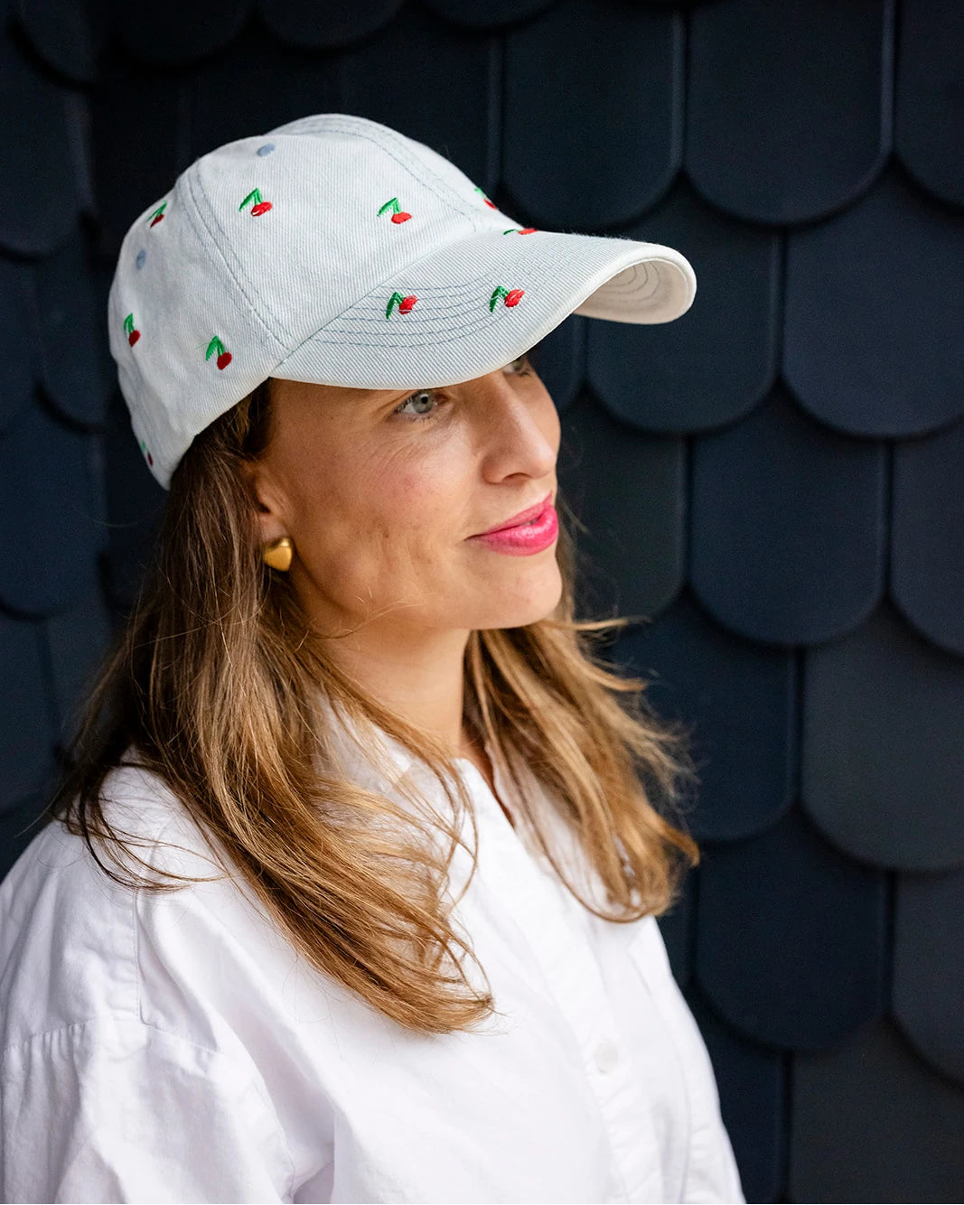 Light-wash denim baseball cap embroidered with small red cherries, front view on a white background.