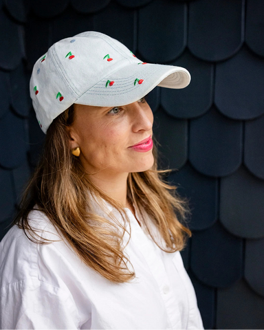 Light-wash denim baseball cap embroidered with small red cherries, front view on a white background.