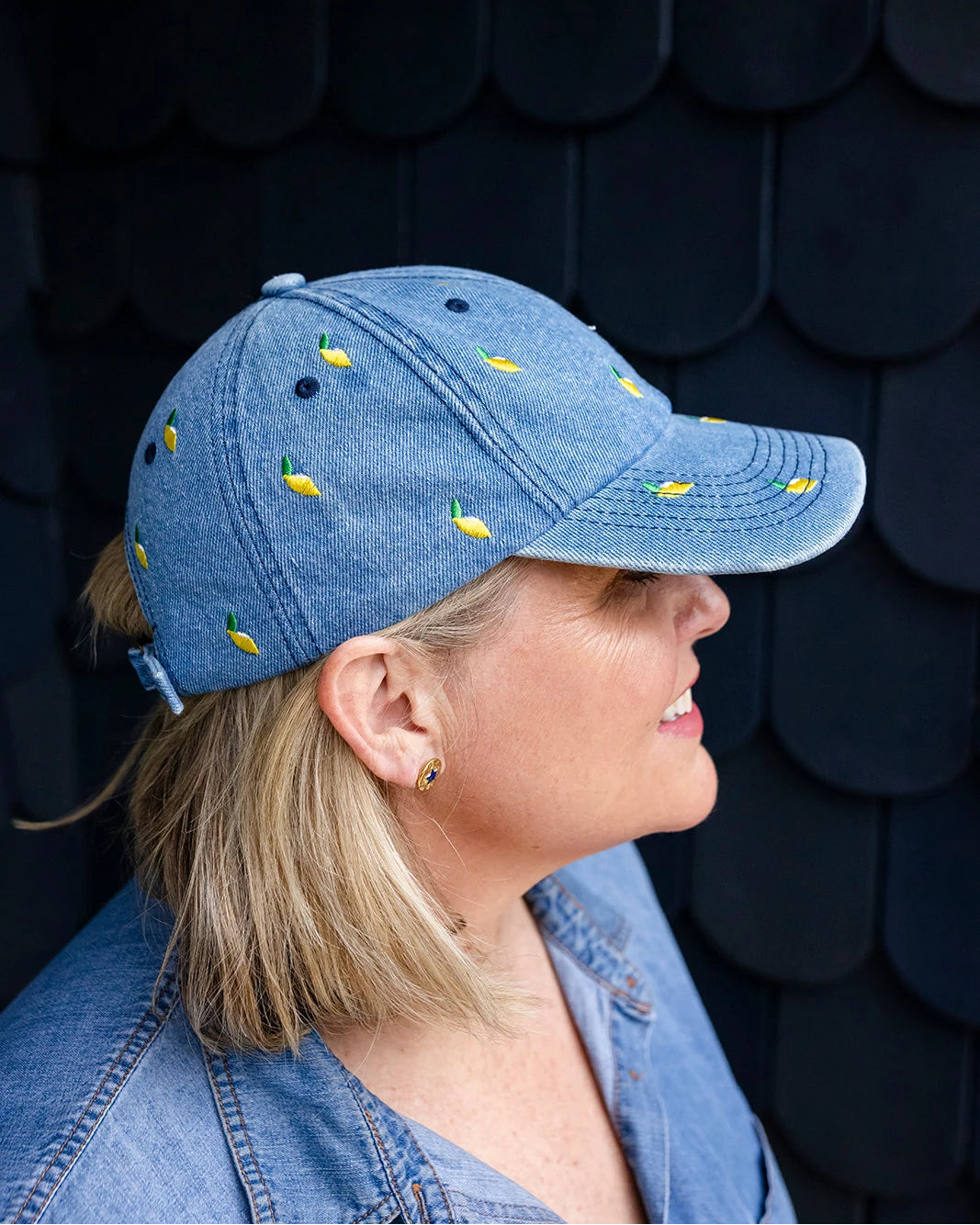Mid-wash denim baseball cap embroidered with small yellow lemons, front view on a white background.