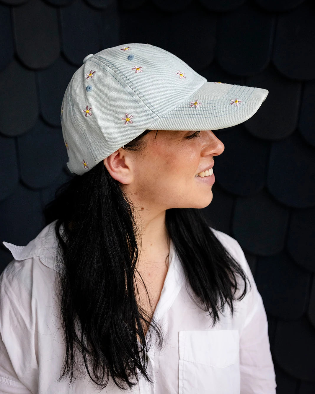 Light-wash denim baseball cap embroidered with pink and yellow flowers, front view on a white background.