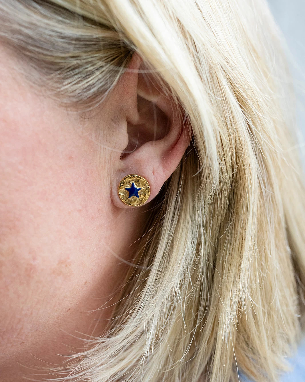 Gold stud earrings with a navy enamel star at the centre