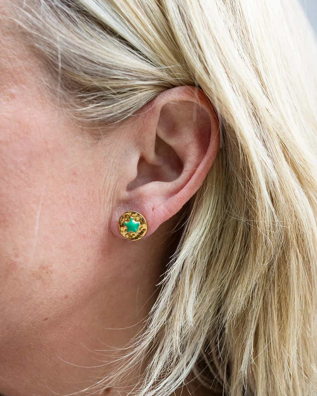 Gold stud earrings with a green enamel star at the centre