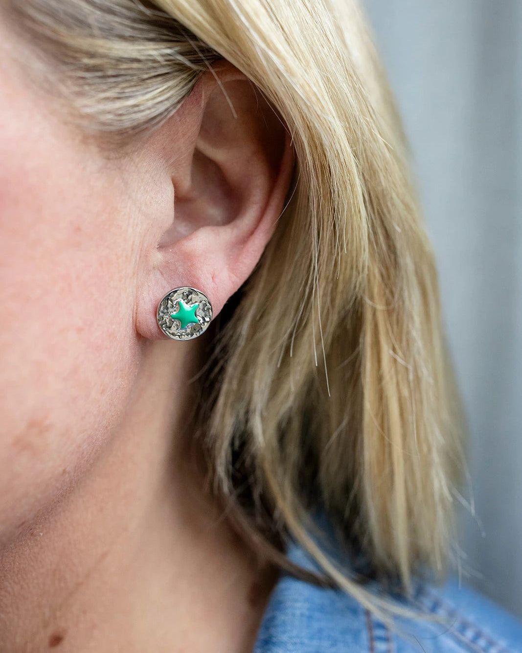 Silver stud earrings with a green enamel star at the centre