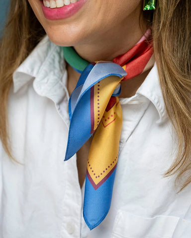 Silk neck scarf in blue, red, green, and mustard colour-block circle print styled around the neck