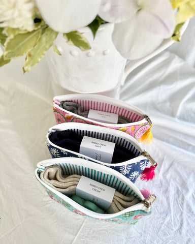 Set of floral-patterned makeup bags on a white surface with flowers in the background