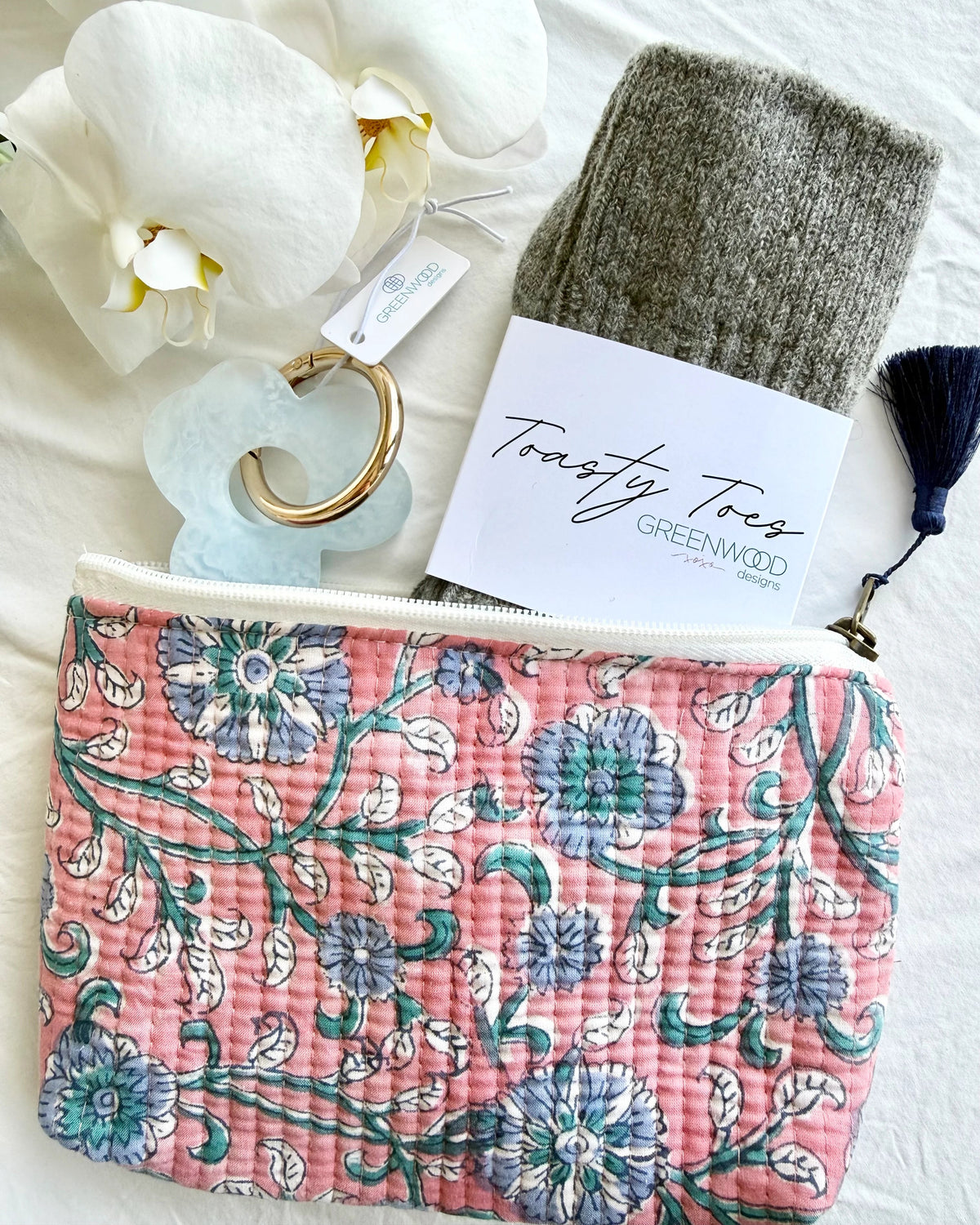 Floral pouch with a tag, white orchid, and gray tassel on a white background