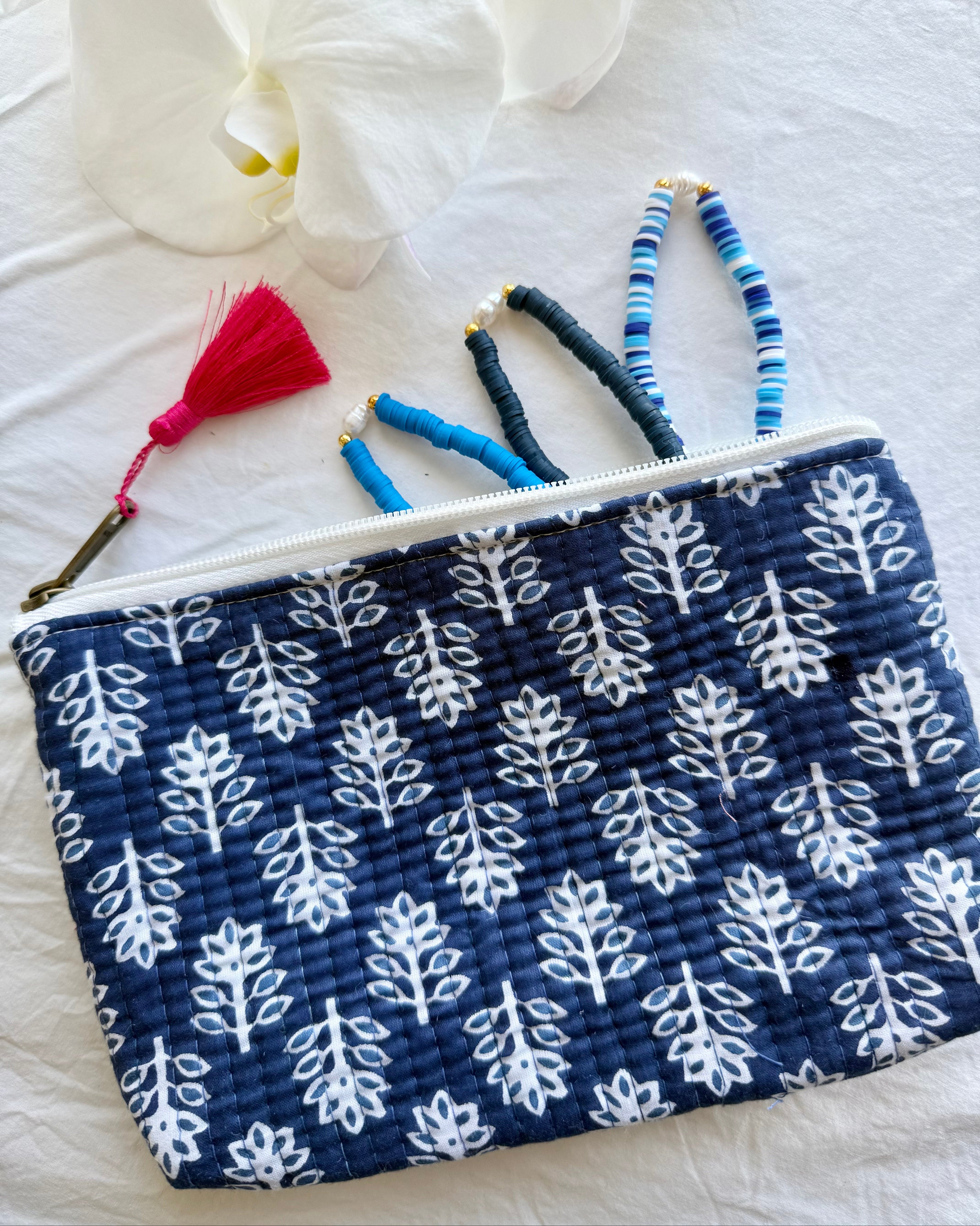 Blue pouch with white leaf pattern and colorful tassels on a white background