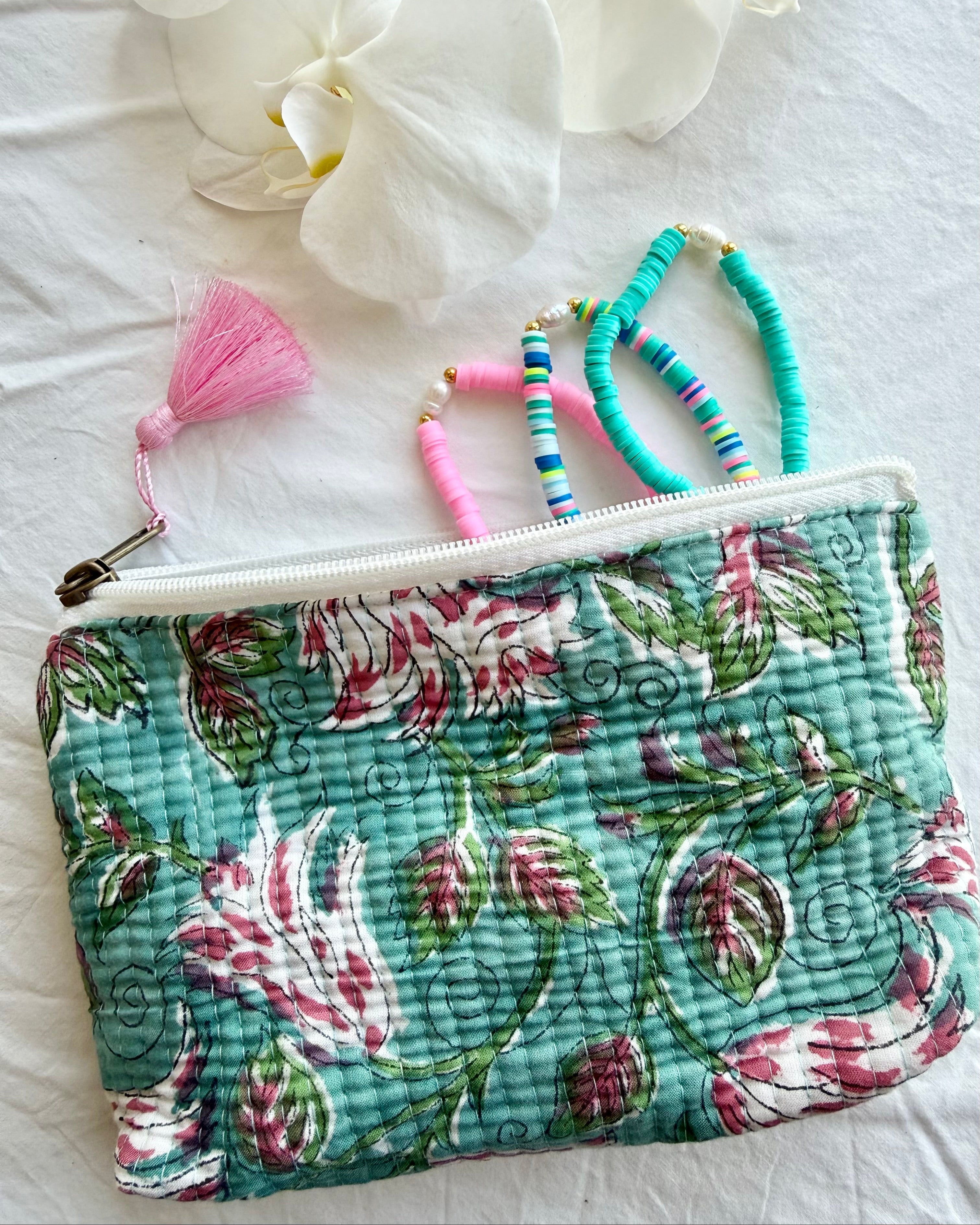 Floral-patterned pouch with jewelry on a white surface