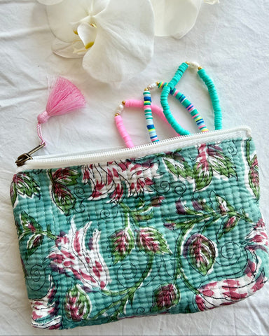 Floral-patterned pouch with jewelry on a white surface