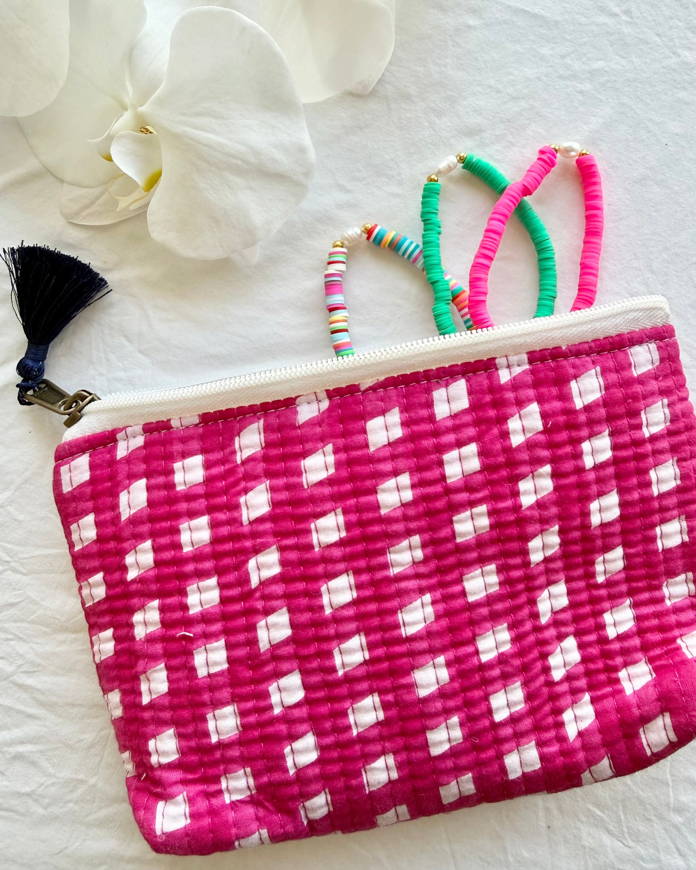 Pink and white checkered pouch with colorful bracelets on a light background