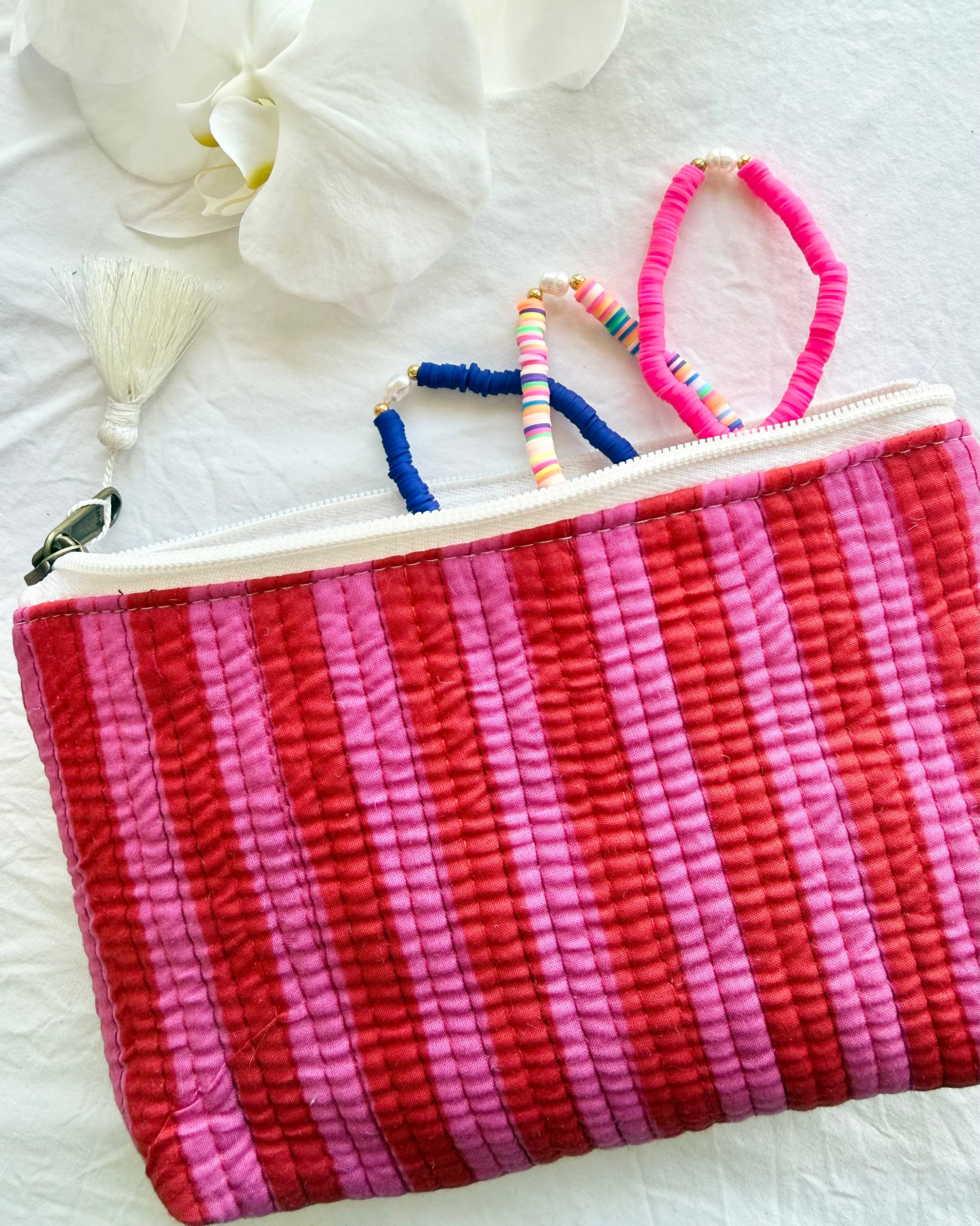 Pink and red striped pouch with colorful hair ties on a white surface