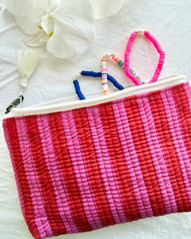 Pink and red striped pouch with colorful hair ties on a white surface