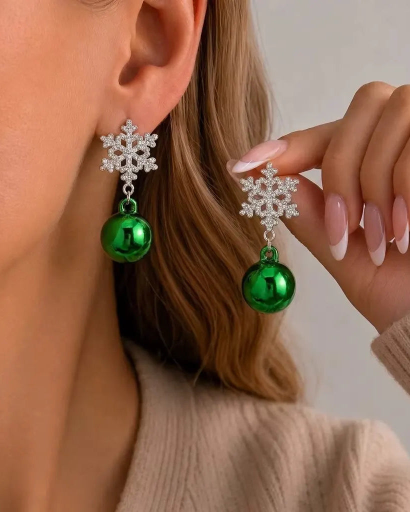 A pair of silver snowflake drop earrings set with clear crystals and shiny green bauble drops.