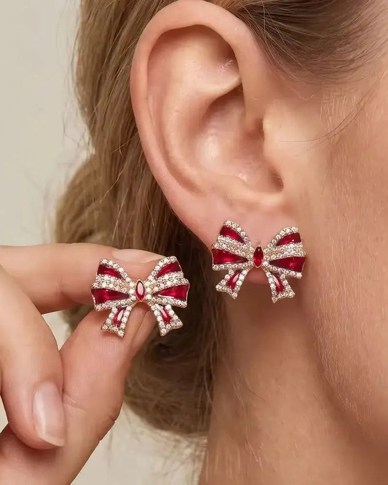 A pair of gold bow stud earrings with red enamel ribbons outlined in clear crystals.