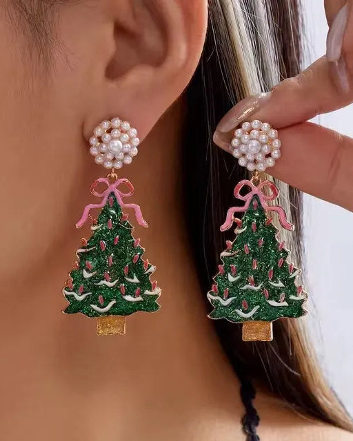 A pair of glittery green Christmas tree drop earrings with pink bows, red and white enamel details, and faux pearl cluster studs.