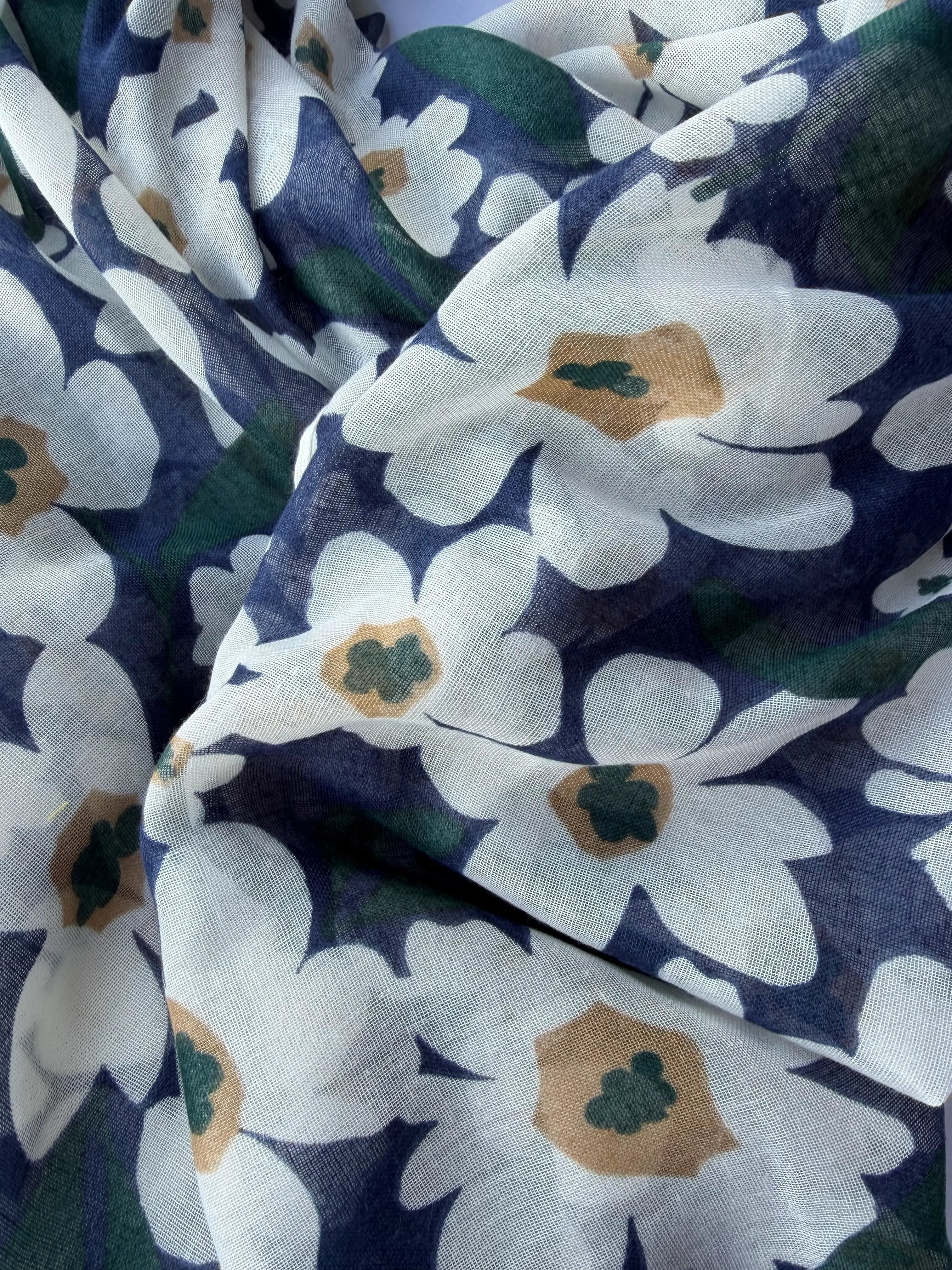 Lightweight navy scarf with large white and tan daisy-style flowers and green leaves, finished with navy and tan tassels