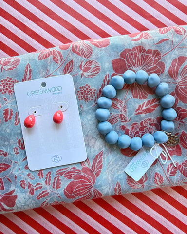 Close-up of the pale blue and coral Gemma floral scarf, the Jacaranda rock bracelet and Alice bright coral teardrop earrings on a Greenwood Designs card.