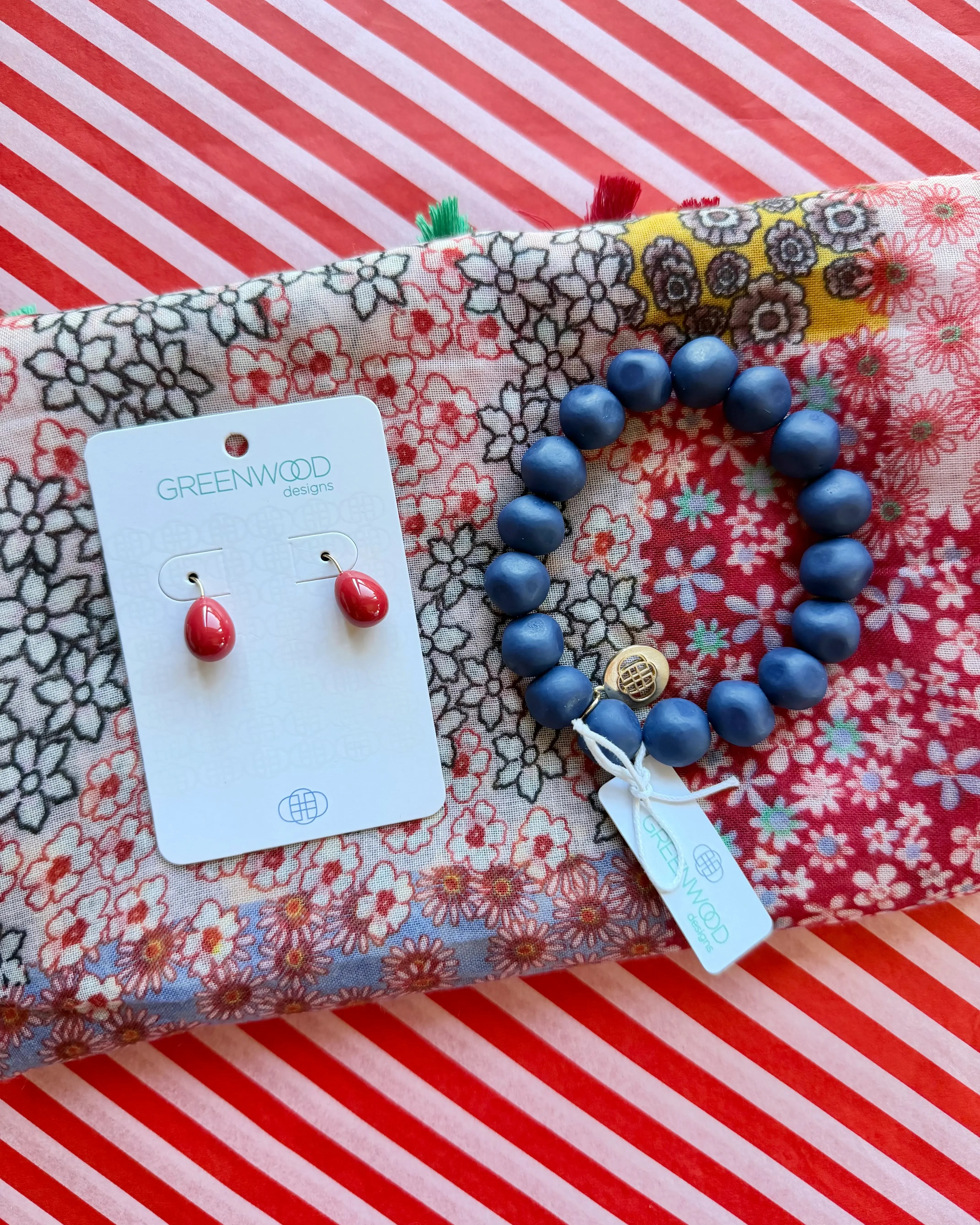 Close-up of the red Willow patchwork floral scarf, the Blue rock bracelet and Alice red teardrop earrings on a Greenwood Designs card.