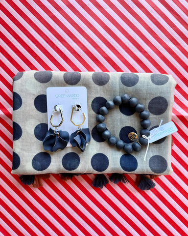 Flat lay of the Nina scarf in taupe with navy polka dots and tassels, the Navy rock bracelet and Petunia earrings in Navy on a Greenwood Designs card.