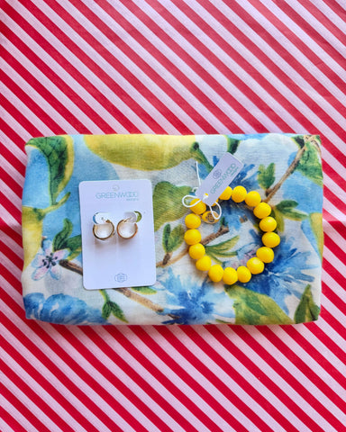 Flat lay of the Iris scarf in a lemon and blue watercolour floral print, the Yellow rock bracelet and Hayley earrings, gold and white enamel huggie hoops, on a Greenwood Designs card.