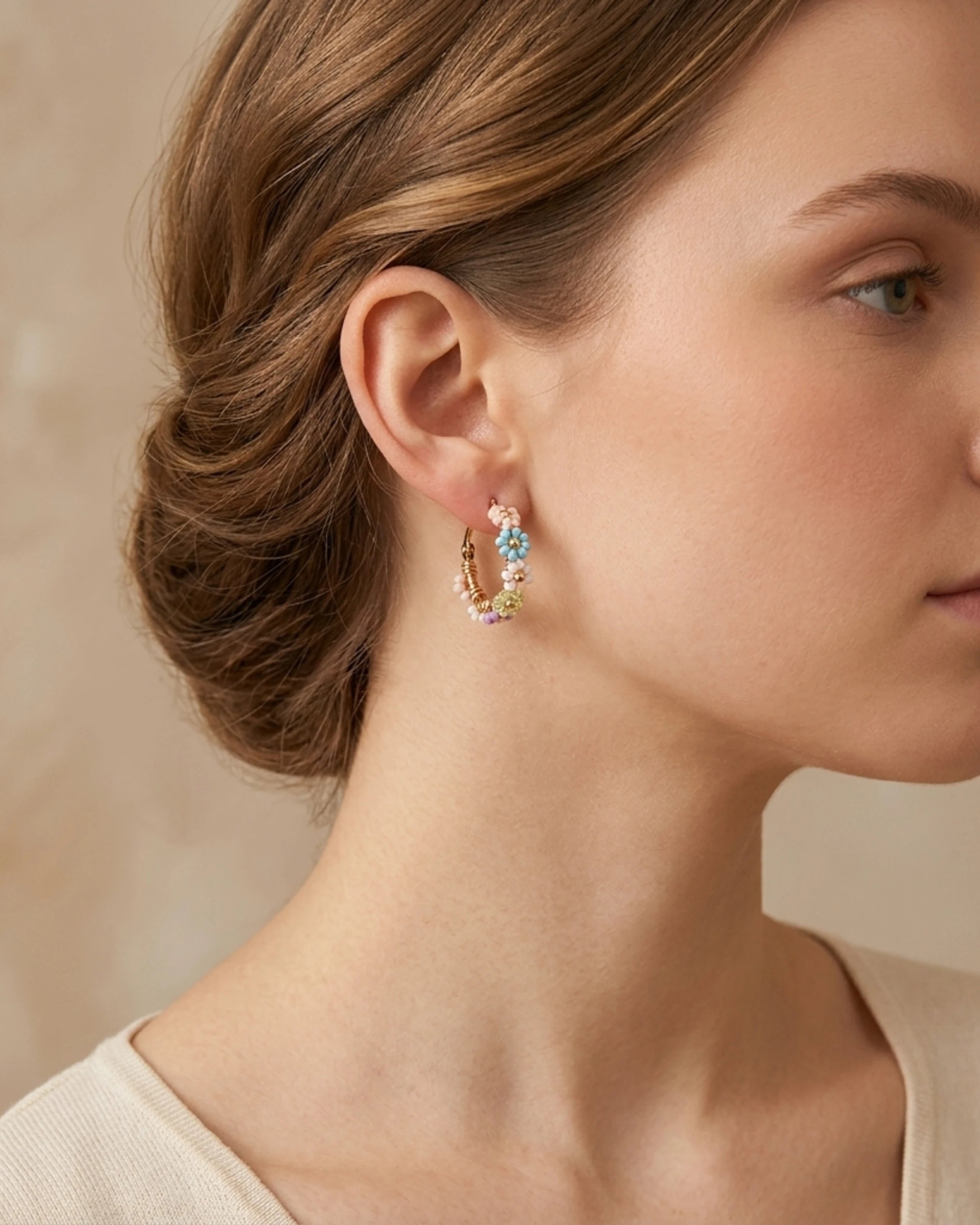 Woman wearing pastel coloured beaded flower gold plated hoop earrings