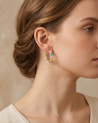 Woman wearing pastel coloured beaded flower gold plated hoop earrings