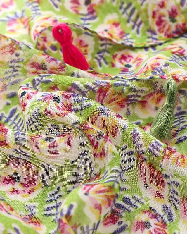 Close-up of green and pink floral print on lightweight scarf fabric with tassel