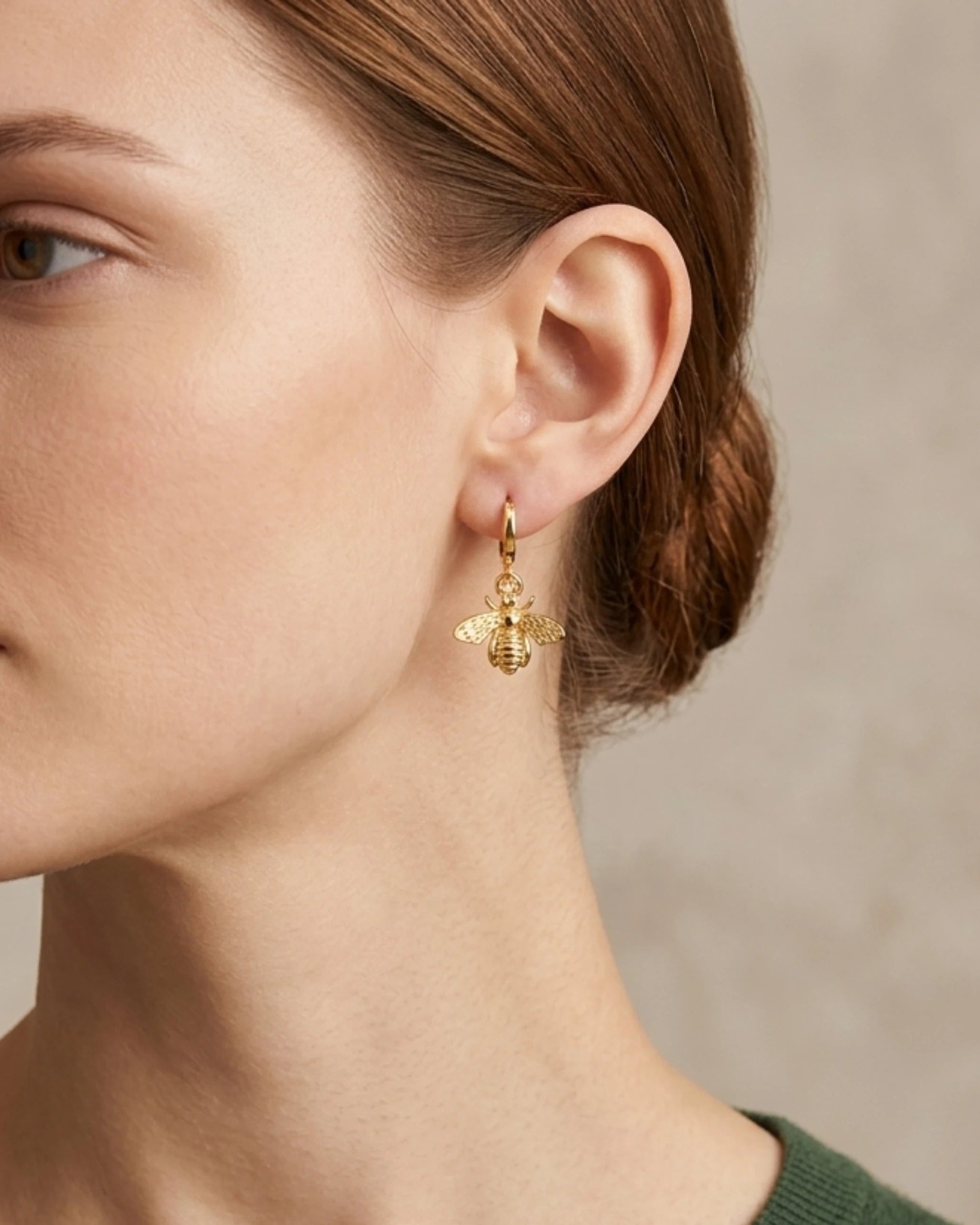 Woman wearing gold hoop earrings with bee dangle