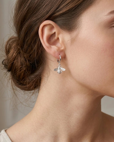 Woman wearing silver hoop earrings with bee dangle