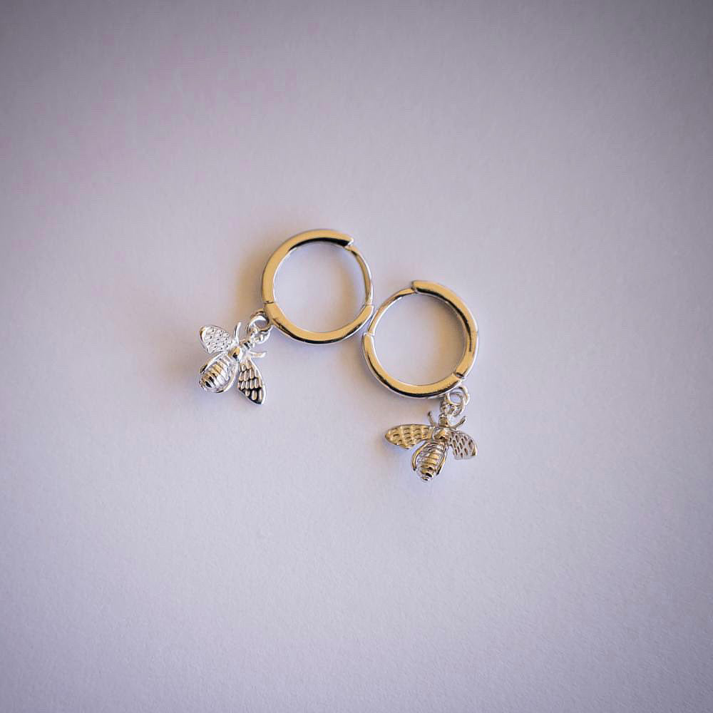 Silver hoop earrings with bee dangle on white background