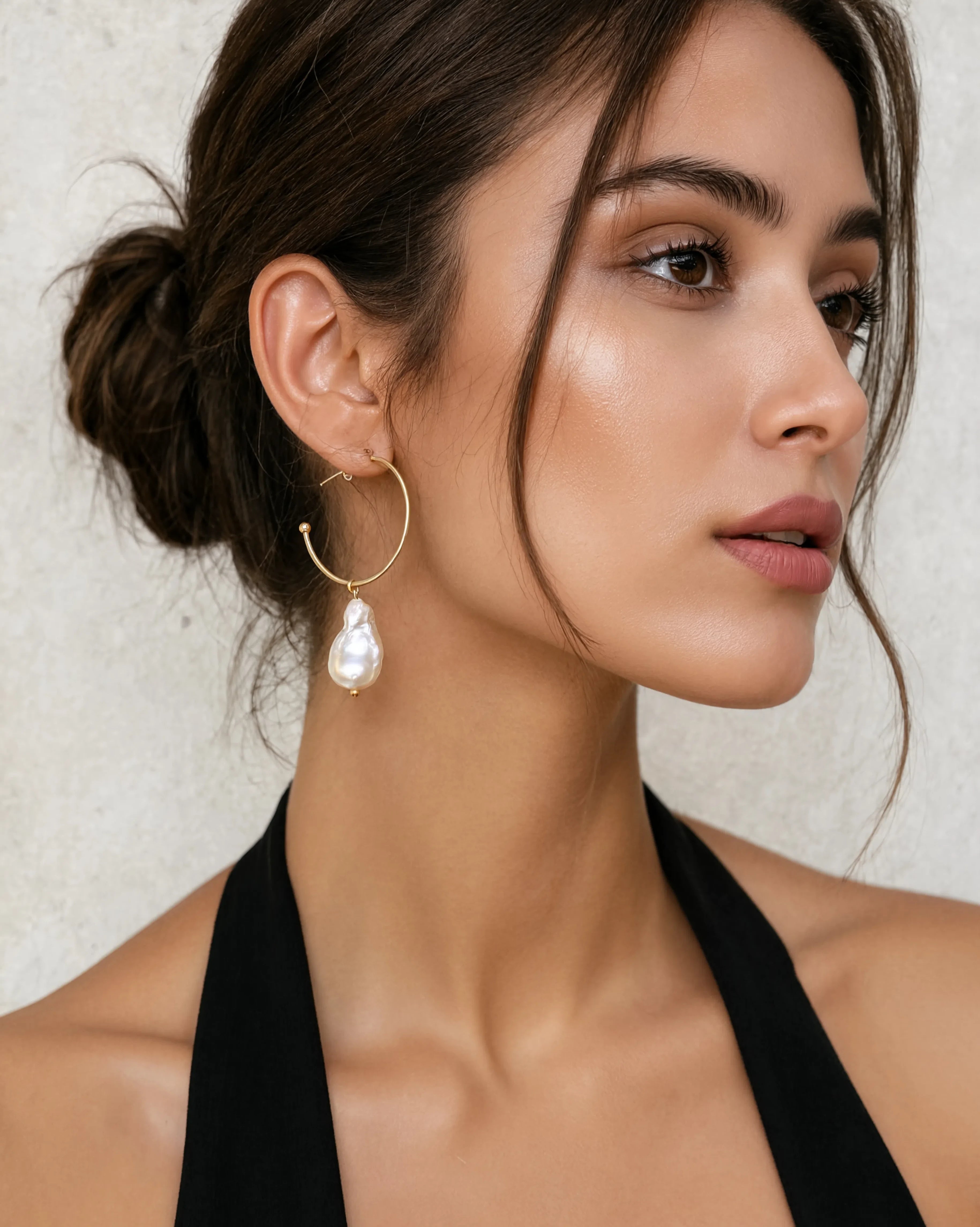 Woman wearing Prue freshwater baroque pearl and gold hoop drop earrings by Greenwood Designs, styled with a black halter top and hair up