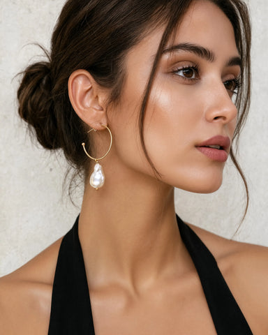 Woman wearing Prue freshwater baroque pearl and gold hoop drop earrings by Greenwood Designs, styled with a black halter top and hair up