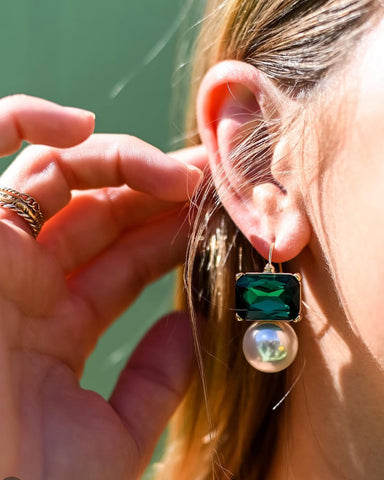 Close-up of a person wearing a green gemstone earring with a blurred background