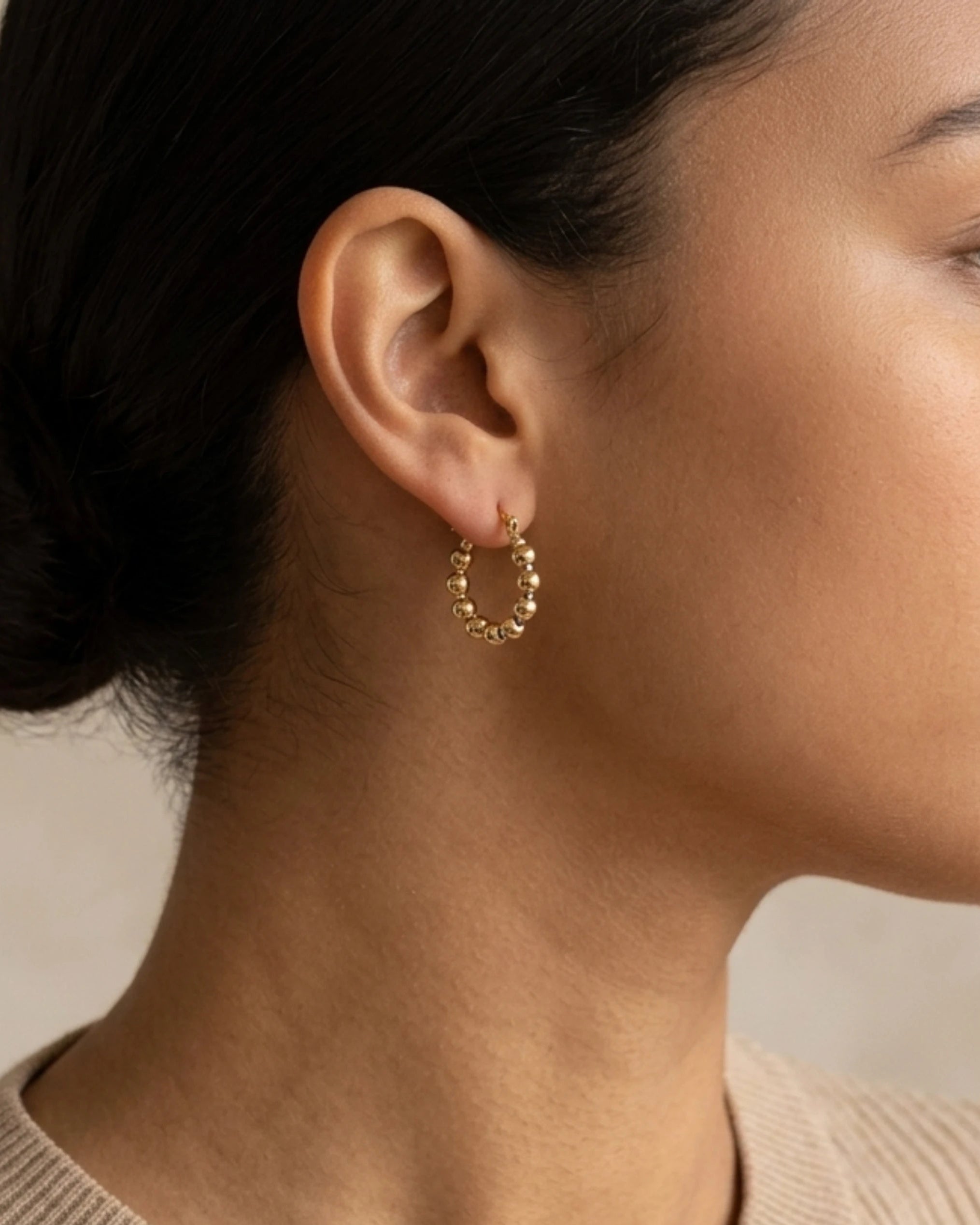 Woman wearing gold ball hoop earrings