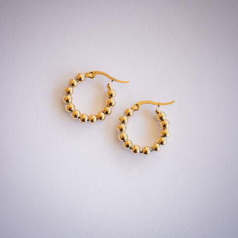 Gold ball hoop earrings on white background