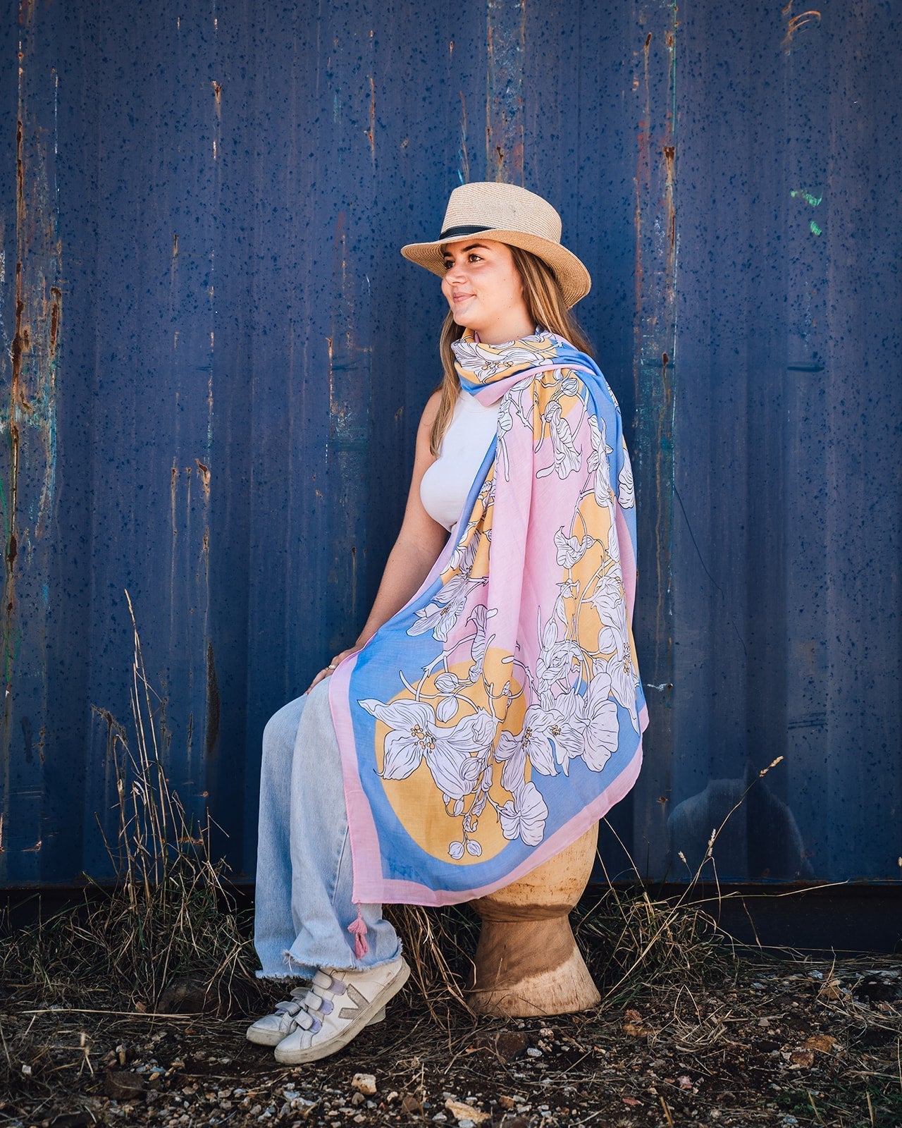 Lily Abstract Floral Women's Scarf: Vibrant abstract design in pink, blue, white, and yellow tones with a whimsical white lily print. Framed with a pretty pink border and finished with playful pink tassels on each corner. Polyester blend for a soft and co