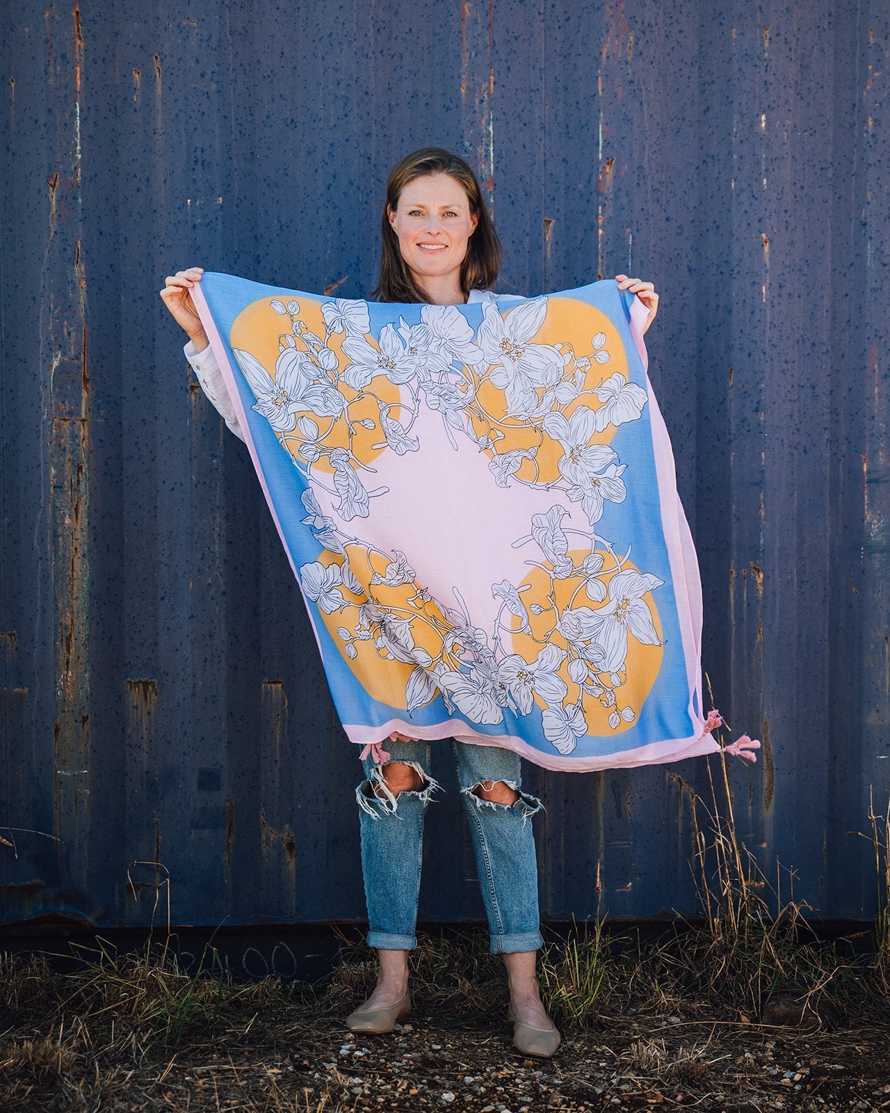 Lily Abstract Floral Women's Scarf: Vibrant abstract design in pink, blue, white, and yellow tones with a whimsical white lily print. Framed with a pretty pink border and finished with playful pink tassels on each corner. Polyester blend for a soft and co